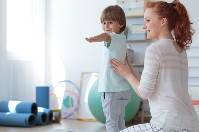 Gimnastyka korekcyjna - fizjoterapeutka ćwicząca z dzieckiem.